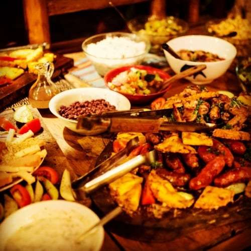 Buffet of rice, beans, salads, grilled sausages and roasted potatoes on a wooden table