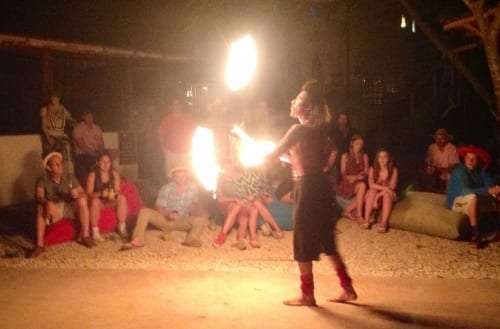 Fire dancer swinging flames at night while seated guests watch