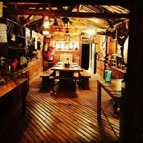 Rustic wooden dining hall with long benches and string lights at night