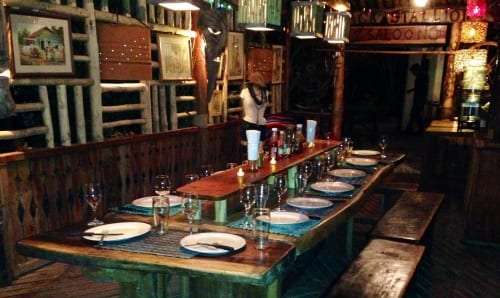 Long candlelit wooden table set with plates and glasses in a rustic restaurant