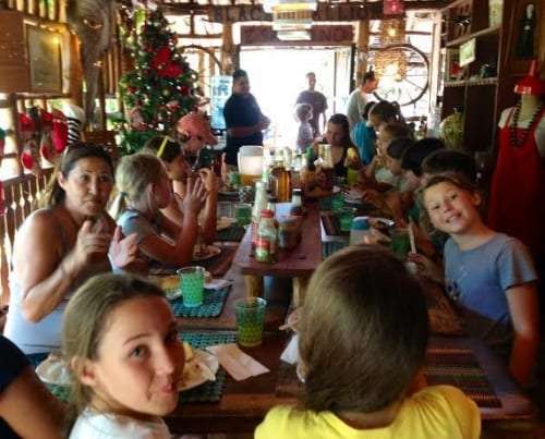Families and children seated at a long table in a restaurant decorated for Christmas