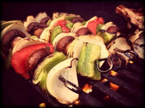 Vegetable skewers with mushrooms, peppers and onions grilling over a flame