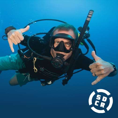 Scuba diver in a mask making a shaka hand sign underwater