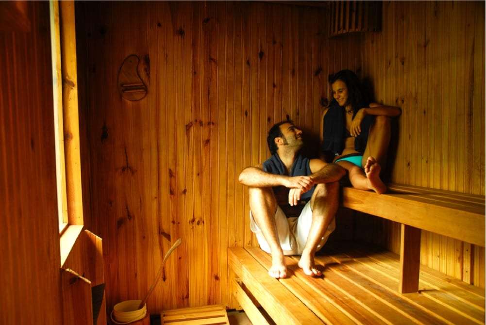 Man and woman sitting and chatting in a wooden sauna