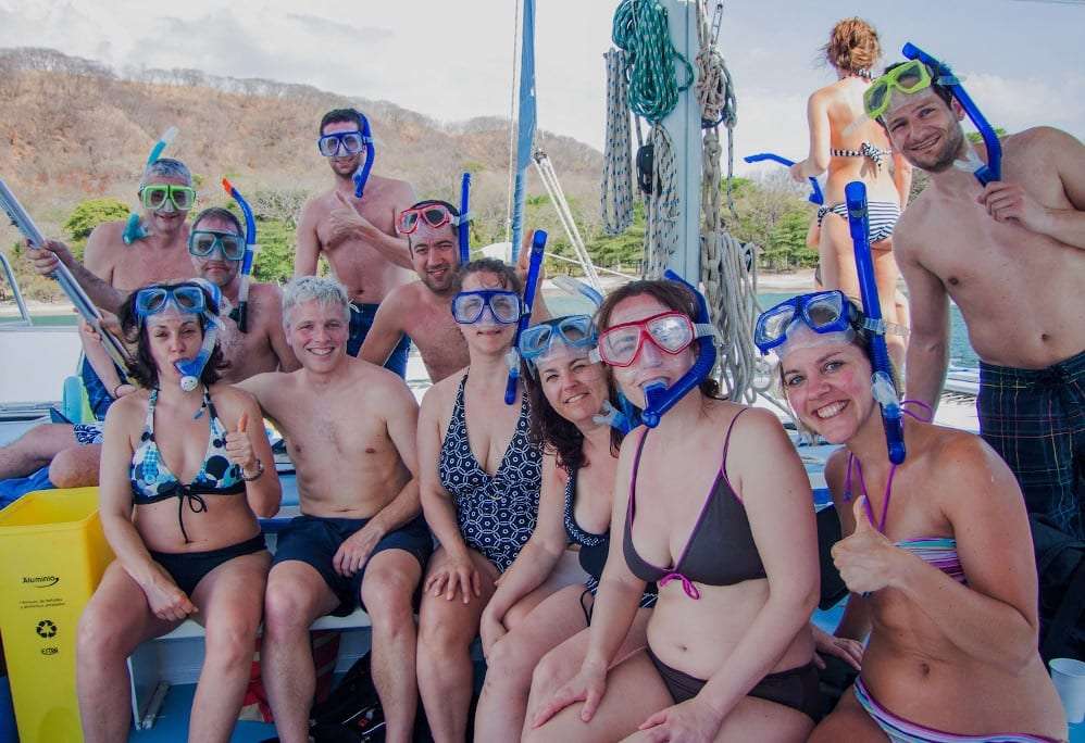 Group of smiling guests in snorkel masks sitting together on a boat