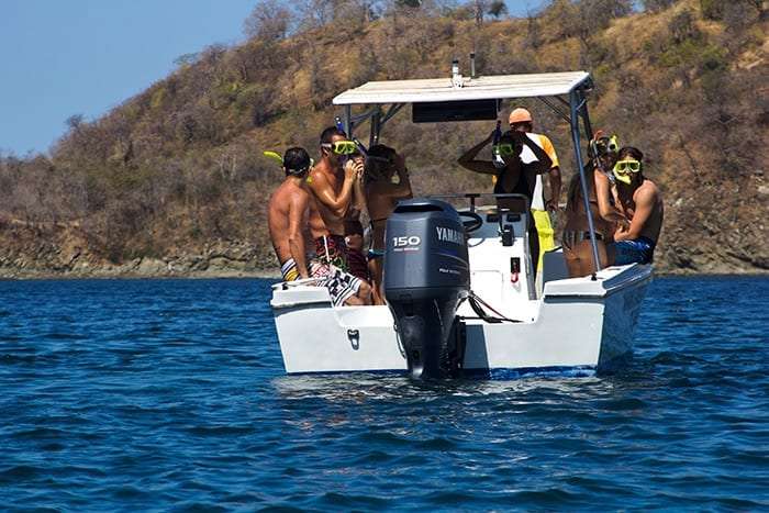 Group in snorkel masks on the back of a white boat with a Yamaha outboard motor