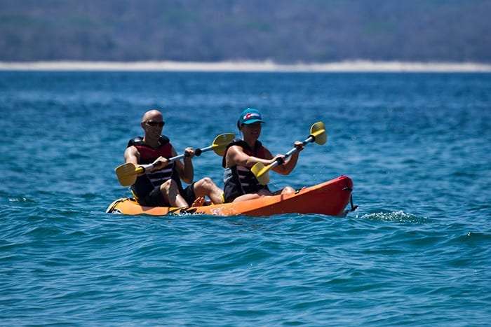 Couple paddling a double kayak across open sea