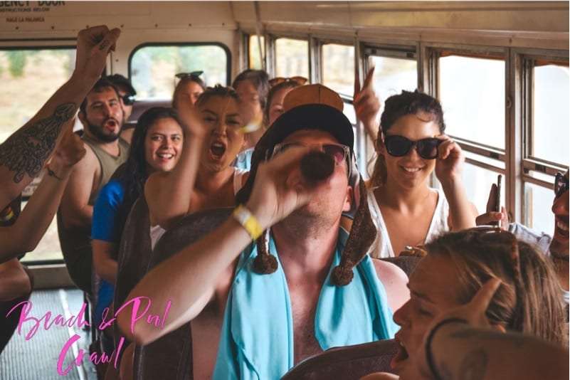 Crowded bus full of cheering passengers, one man drinking from a bottle