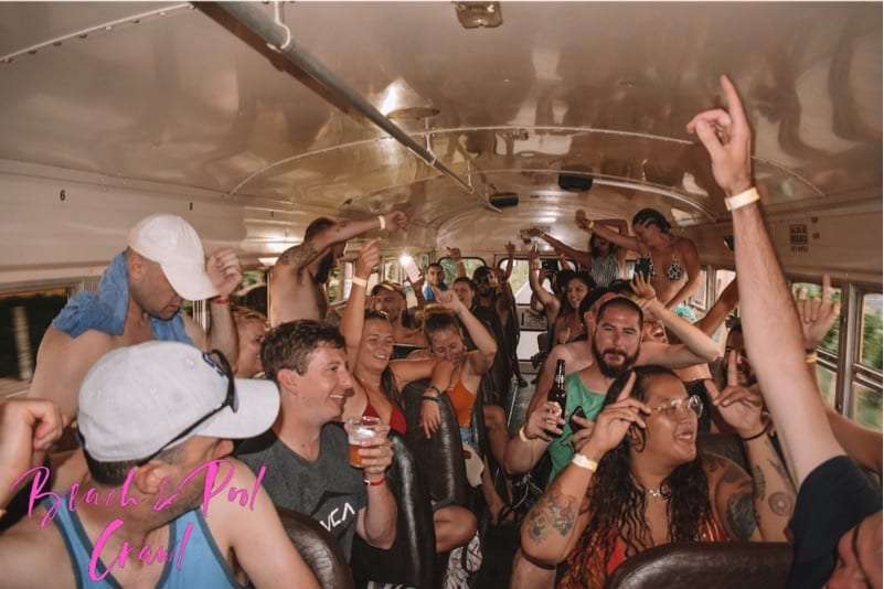 Passengers dancing with raised hands on a crowded party bus