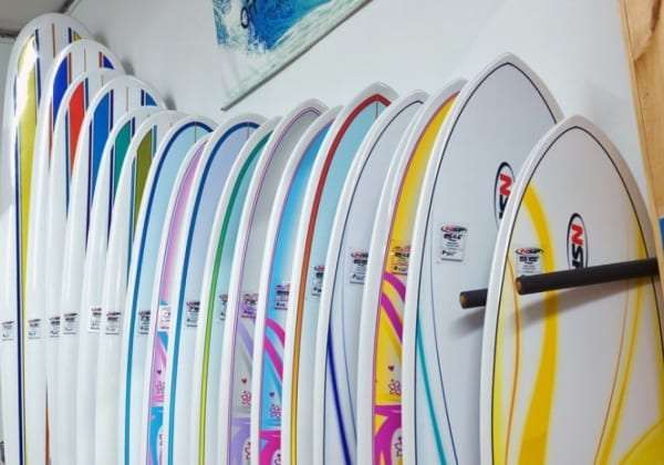 Row of colorful surfboards stored upright against a wall