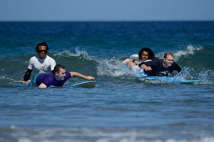 Instructor and two students paddling on surfboards in the sea