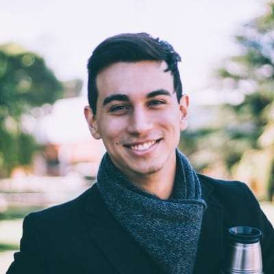 Portrait of Jay Simon, a smiling man with short dark hair in a dark coat and scarf