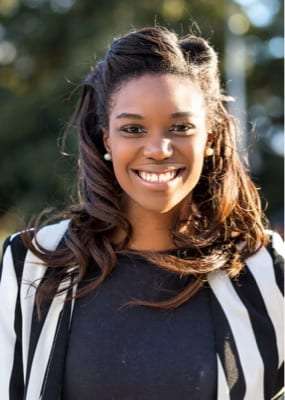 Portrait of Tania Smith, a smiling woman with long dark wavy hair in a striped jacket