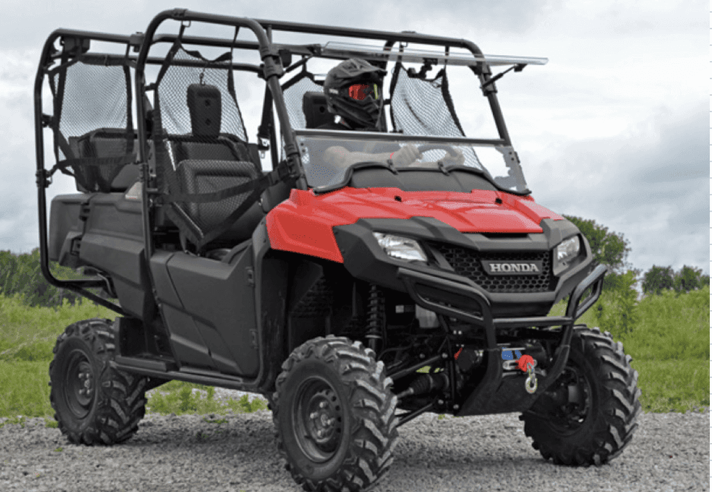 Red Honda side by side utility vehicle with a roll cage parked on gravel