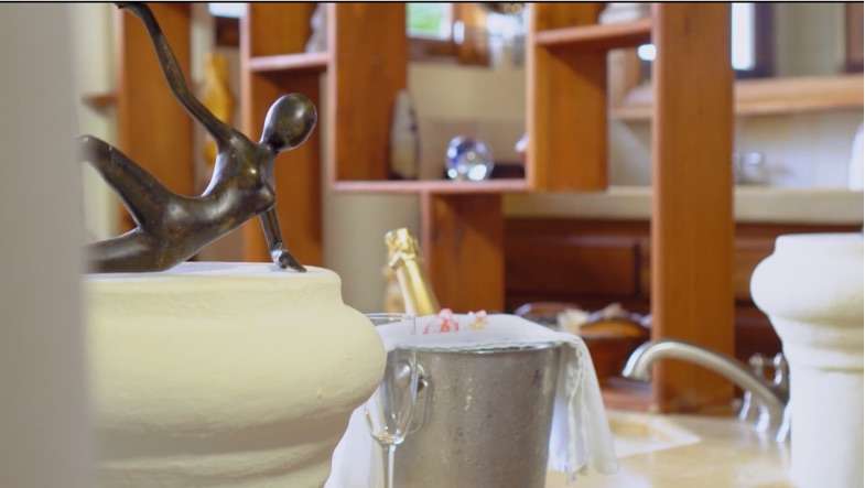 Champagne chilling in a metal bucket with a glass in a wooden-shelved spa room